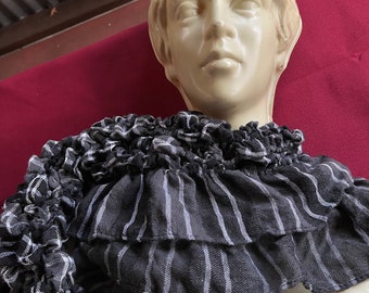 May include: A white mannequin head with a black and white striped ruffled collar. The collar is made of fabric and has a layered design.
