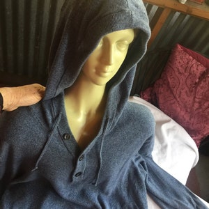 May include: A blue hooded sweater with a button-up front and long sleeves. The sweater is made of a soft, knit fabric.
