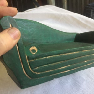 May include: A miniature green wooden couch with gold trim. The couch has a curved back and a slightly raised seat.