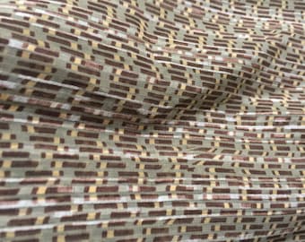May include: A close-up of a fabric with a geometric pattern. The fabric is a light green color with brown and yellow stripes.