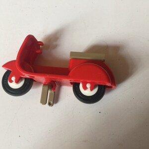 May include: A red toy scooter with a white and black tire, a white and black tire, and a beige top.