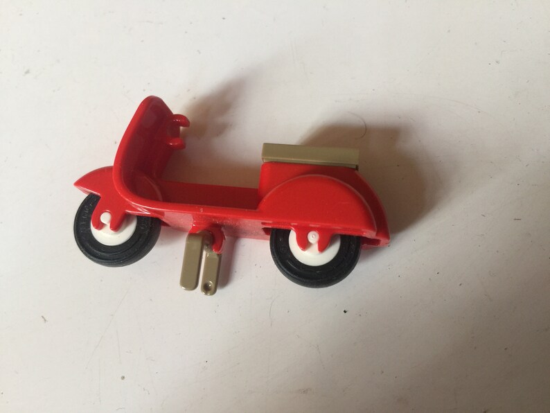 May include: A red toy scooter with a white and black tire, a white and black tire, and a beige top.