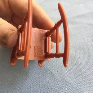 K&ouml;nnte beinhalten: Ein brauner Plastik-Schaukelstuhl mit der Aufschrift "L.K.C. Copy Right" auf der Unterseite.