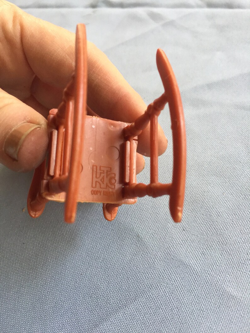 K&ouml;nnte beinhalten: Ein brauner Plastik-Schaukelstuhl mit der Aufschrift "L.K.C. Copy Right" auf der Unterseite.
