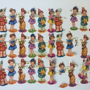Peut inclure: Un ensemble de 24 poup&eacute;es en papier vintage, chacune repr&eacute;sentant un enfant habill&eacute; d'un costume color&eacute;. Les poup&eacute;es tiennent divers instruments de musique, dont une guitare, un tambour, une trompette et un tambourin. Les poup&eacute;es sont imprim&eacute;es sur du papier &eacute;pais et sont en bon &eacute;tat.