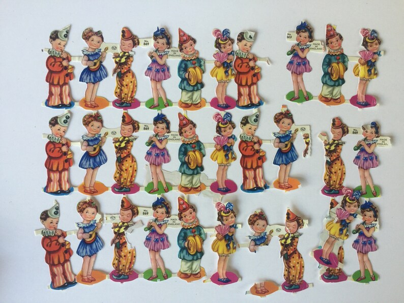 Peut inclure: Un ensemble de 24 poup&eacute;es en papier vintage, chacune repr&eacute;sentant un enfant habill&eacute; d'un costume color&eacute;. Les poup&eacute;es tiennent divers instruments de musique, dont une guitare, un tambour, une trompette et un tambourin. Les poup&eacute;es sont imprim&eacute;es sur du papier &eacute;pais et sont en bon &eacute;tat.