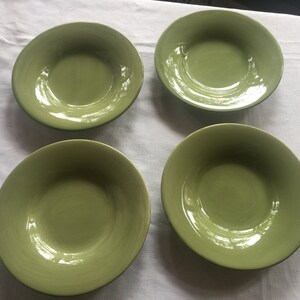 May include: Four green ceramic bowls with a glossy finish. The bowls are all the same size and shape, and they have a slightly rounded bottom.