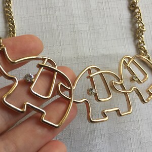May include: Gold necklace with three linked elephant pendants, each with a clear rhinestone in the center.