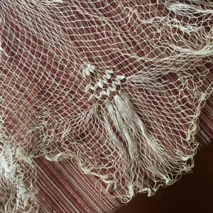May include: A white net with a fine mesh pattern. The net has a frayed edge and is made of a delicate material.