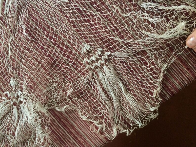 May include: A white net with a fine mesh pattern. The net has a frayed edge and is made of a delicate material.