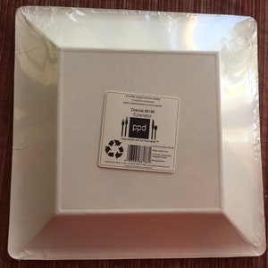 May include: A package of 8 white, square, disposable dinner plates. The package is labeled "Dracula 801186" and "Plated Kitchen" with a logo that says "ppd". The plates are made from plant-based materials and are compostable.