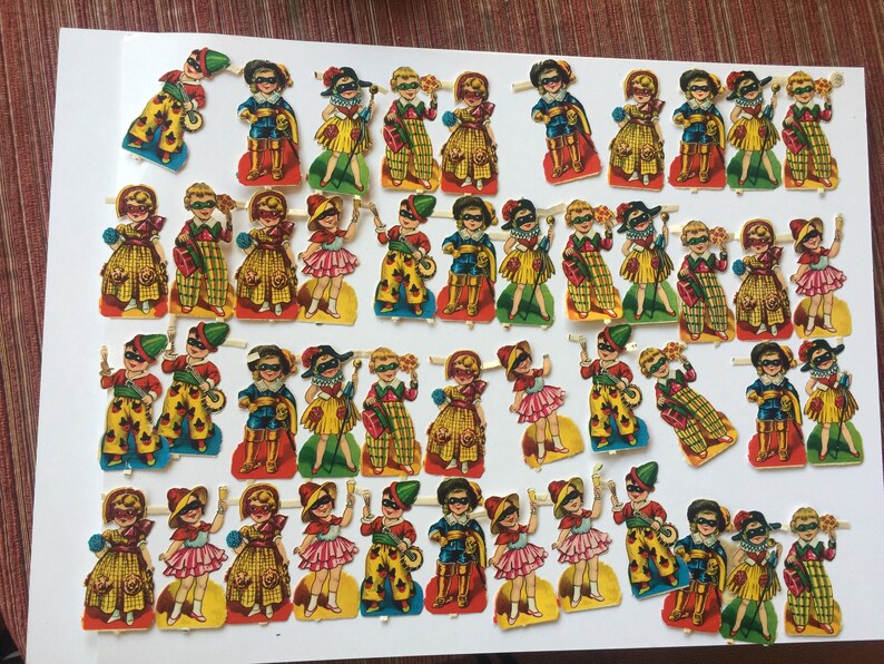 Peut inclure: Une collection de 40 poup&eacute;es en papier vintage, chacune portant un costume color&eacute; diff&eacute;rent. Les poup&eacute;es sont toutes habill&eacute;es en tenue de mascarade, avec des masques et des chapeaux. Les poup&eacute;es sont imprim&eacute;es sur du papier &eacute;pais et sont en excellent &eacute;tat.