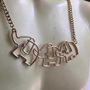 May include: Gold necklace with three connected elephant charms, each with a small clear rhinestone in the center.