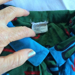 K&ouml;nnte beinhalten: Ein gr&uuml;n-blau-rot-schwarz gemustertes Hemd mit blauem Kragen. Das Hemd hat ein Etikett mit der Aufschrift "48" und "Style 5578".