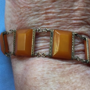 May include: A vintage amber and silver bracelet with a chain link design. The bracelet features four rectangular amber stones set in silver frames.