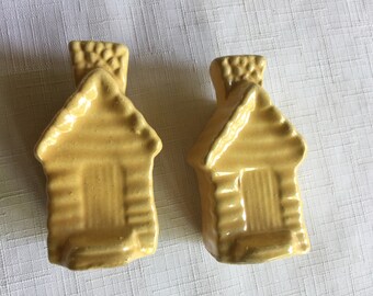 May include: Two yellow ceramic salt and pepper shakers shaped like log cabins with a chimney on top.