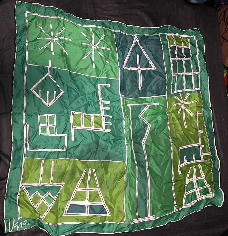 May include: A green silk scarf with a geometric pattern of white lines. The pattern includes stars, trees, and other abstract shapes.
