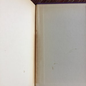 May include: An open book with a purple cover and white pages. The pages are slightly yellowed with age and there are a few brown spots on the right page.