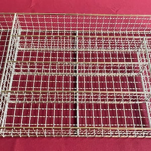 Puede incluir: Un organizador de cubiertos de malla de alambre plateado con múltiples compartimentos. El organizador está diseñado para contener cubiertos y utensilios.