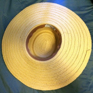 Pu&ograve; includere: Un cappello di paglia a tesa larga con una fascia in pelle marrone. Il cappello &egrave; fatto di paglia intrecciata e ha un colore naturale.