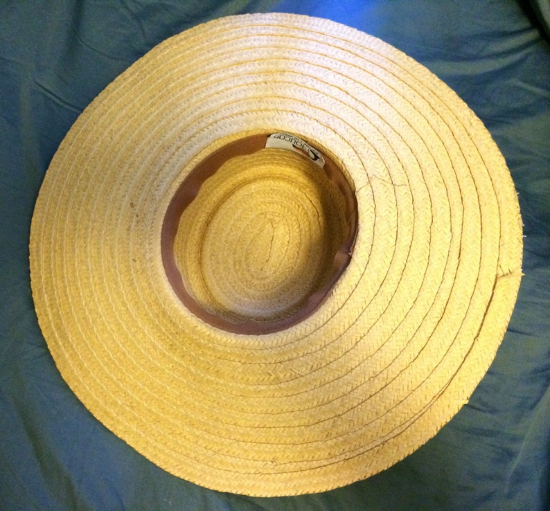 Pu&ograve; includere: Un cappello di paglia a tesa larga con una fascia in pelle marrone. Il cappello &egrave; fatto di paglia intrecciata e ha un colore naturale.