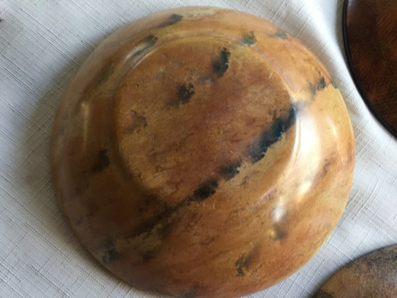 May include: A wooden bowl with a brown and black mottled finish. The bowl is round and has a slight lip around the edge.