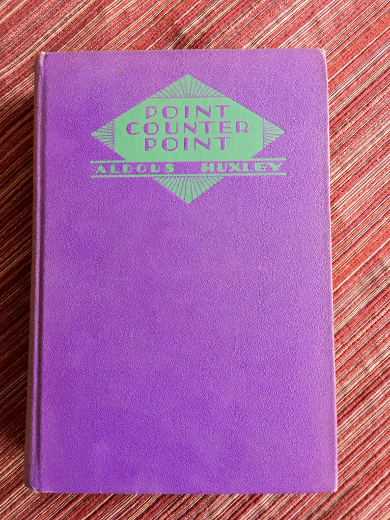May include: A purple hardcover book with the title "Point Counter Point" by Aldous Huxley printed in green on the front cover.