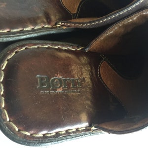 May include: Close-up of the inside of a brown leather shoe with the brand name "Born" and the text "Hand Crafted Footwear" embossed on the insole.