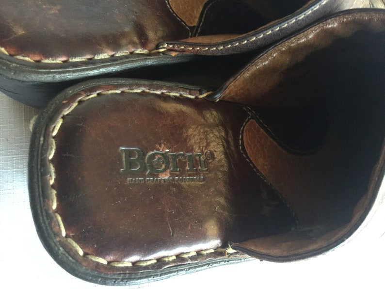 May include: Close-up of the inside of a brown leather shoe with the brand name "Born" and the text "Hand Crafted Footwear" embossed on the insole.