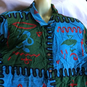 K&ouml;nnte beinhalten: Ein lang&auml;rmliges Hemd mit Kn&ouml;pfen und einem blauen, gr&uuml;nen und roten Muster. Das Hemd zeigt verschiedene abstrakte Formen und Symbole.