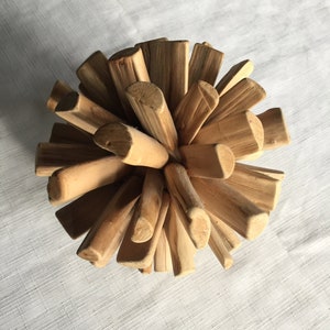 May include: A wooden sphere sculpture made of many small, natural-colored sticks. The sticks are arranged in a radial pattern, creating a unique and organic design.