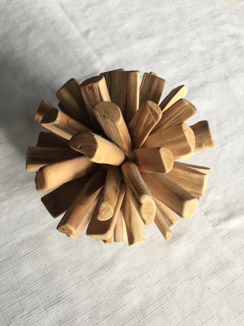 May include: A wooden sphere sculpture made of many small, natural-colored sticks. The sticks are arranged in a radial pattern, creating a unique and organic design.