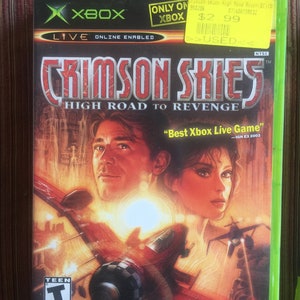 May include: Xbox video game case for Crimson Skies: High Road to Revenge. The case features a red, white, and blue color scheme with a picture of a plane flying through the air. The text "Best Xbox Live Game" is printed on the case.