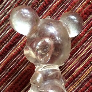 Puede incluir: Una figurita de pl&aacute;stico transparente de Mickey Mouse. La figurita est&aacute; de pie con los brazos a los lados. La figurita es un juguete vintage.