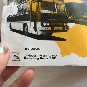 May include: A black and white photo of a bus with the text "Novosti Press Agency Publishing House, 1986" and the number "3601000000".