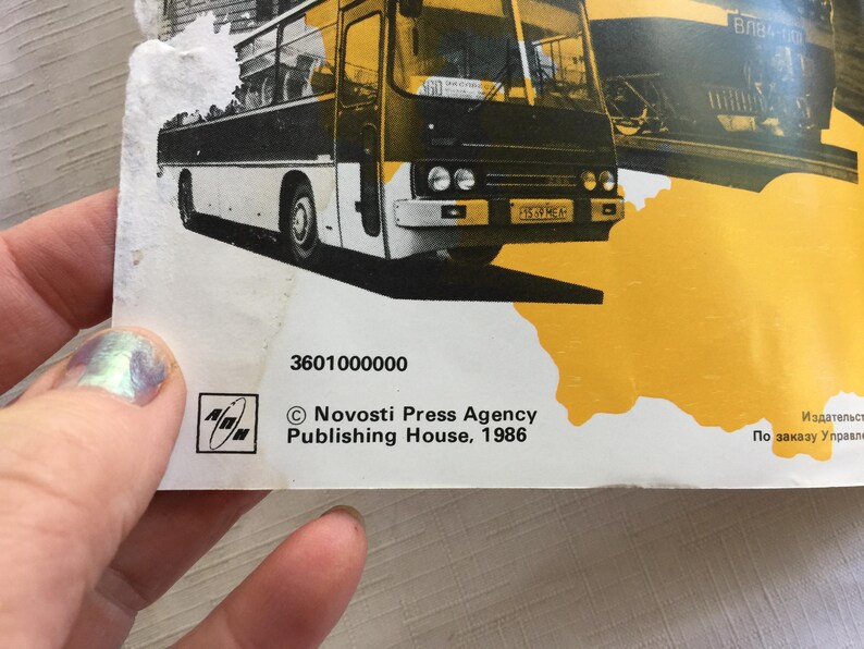 May include: A black and white photo of a bus with the text "Novosti Press Agency Publishing House, 1986" and the number "3601000000".