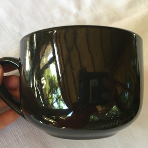 May include: A large, black ceramic mug with a glossy finish and a rounded handle.