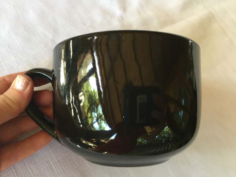 May include: A large, black ceramic mug with a glossy finish and a rounded handle.