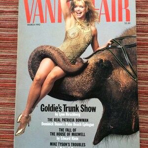Op de afbeelding: Een tijdschriftcover met een vrouw in een gouden paillettentop die op een olifant rijdt. Het tijdschrift heet "Vanity Fair" en het omslagverhaal is "Goldie's Trunk Show".