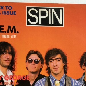 May include: A magazine cover featuring the band R.E.M. with the text "Back to Jail Issue" and "Are We There Yet?" The cover also features a photo of Boy George with the text "Boy George Exclusive Interview".
