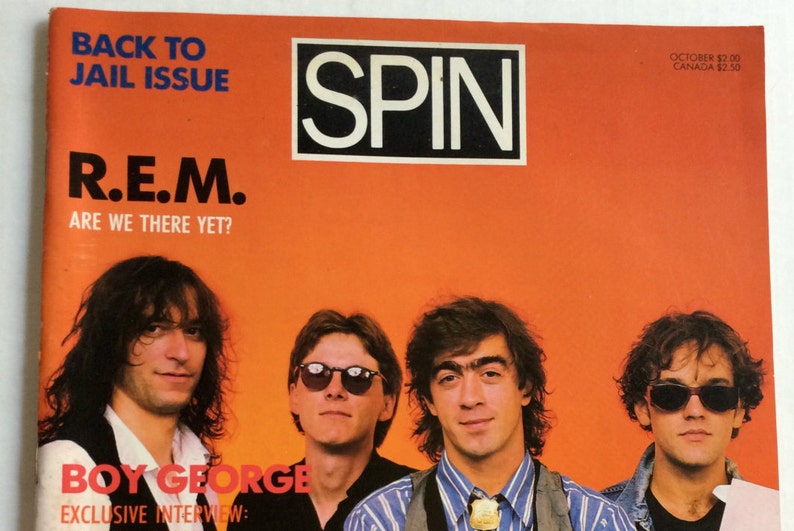 May include: A magazine cover featuring the band R.E.M. with the text "Back to Jail Issue" and "Are We There Yet?" The cover also features a photo of Boy George with the text "Boy George Exclusive Interview".