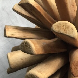 May include: A wooden puzzle ball made of multiple pieces of wood that are interlocked together. The ball is made of light brown wood and has a natural finish.