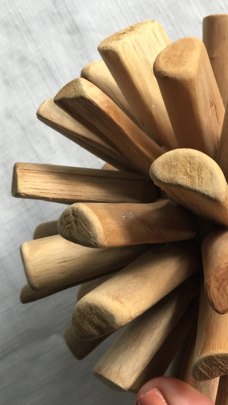 May include: A wooden puzzle ball made of multiple pieces of wood that are interlocked together. The ball is made of light brown wood and has a natural finish.