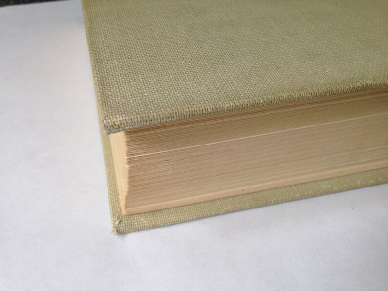 May include: Close-up of the spine of a hardcover book with a light green fabric cover. The pages are visible and the book is closed.