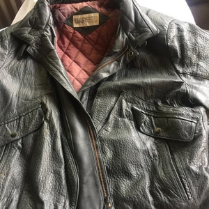 Pu&ograve; includere: Una giacca bomber in pelle nera con chiusura a zip e fodera trapuntata. La giacca ha un'etichetta che dice "G.A.R.S.E.L."
