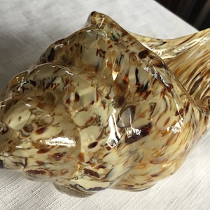 May include: A glass seashell sculpture with a swirl pattern in shades of brown and white.