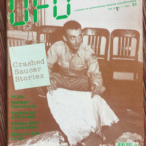 Puede incluir: Un n&uacute;mero de 1991 de la revista UFO, volumen 6, n&uacute;mero 1, con una fotograf&iacute;a de portada en tono sepia de una persona examinando restos met&aacute;licos. La portada incluye el texto UFO, Crashed Saucer Stories, Roswell Resurfaces, Kecksburg UFO Crash y Human-Alien Declaration.