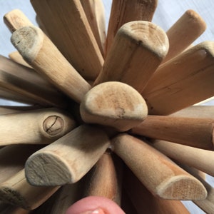 May include: A wooden ball sculpture made of many small, light brown sticks. The sticks are arranged in a radial pattern, creating a sphere shape. The sculpture is a unique and decorative piece.
