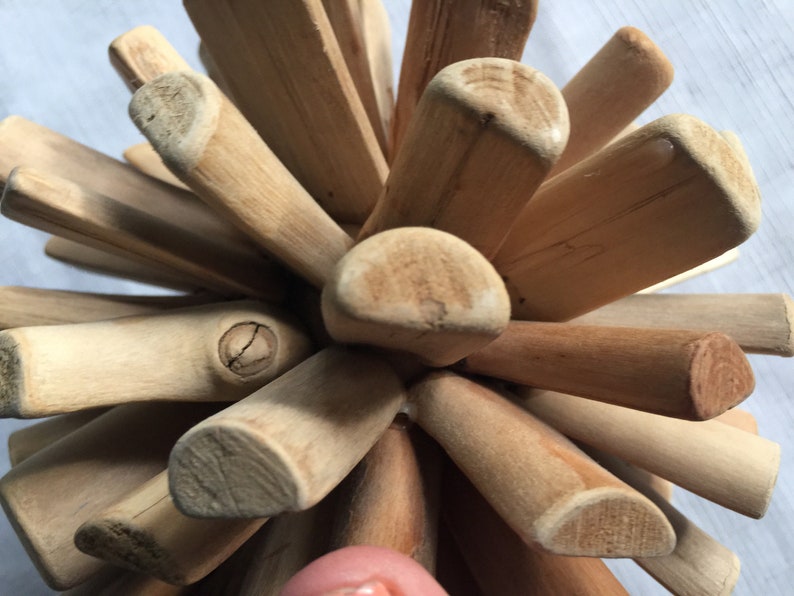 May include: A wooden ball sculpture made of many small, light brown sticks. The sticks are arranged in a radial pattern, creating a sphere shape. The sculpture is a unique and decorative piece.