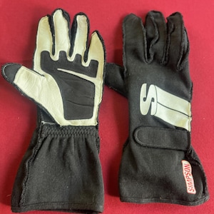 Puede incluir: Un par de guantes de carreras en blanco y negro. Los guantes tienen un pu&ntilde;o negro y una zona de palma y dedos blanca. La marca "SIMPSON" es visible en la correa de la mu&ntilde;eca.